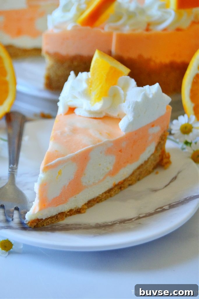 closeup of a slice of orange creamsicle cheesecake on a white marble plate