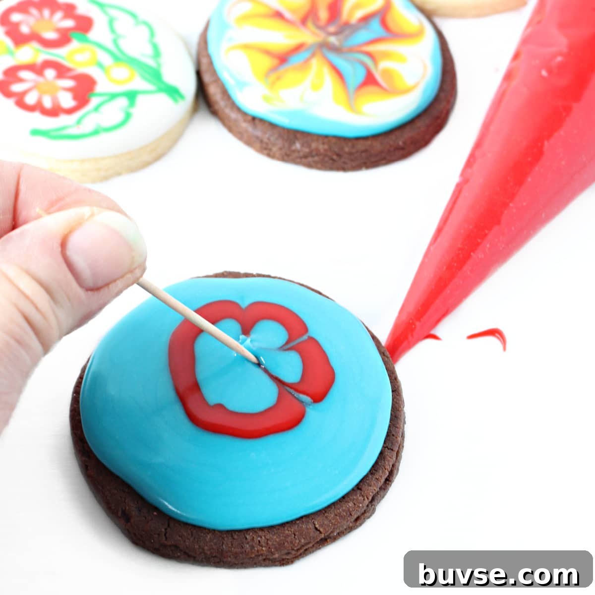 Glaze Icing Recipe for Cakes, Donuts, and Pastries 9 Dragging toothpick in glaze icing on a chocolate sugar cookie to make a flower.