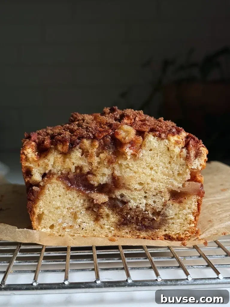 Close-up of sliced apple fritter bread on a cooling rack, with fresh apples in the background.