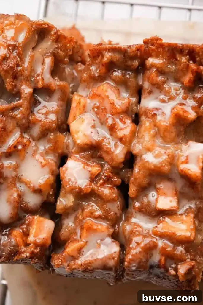 Overhead view of apple fritter bread topped with diced apples and drizzled glaze, cut into thick slices.