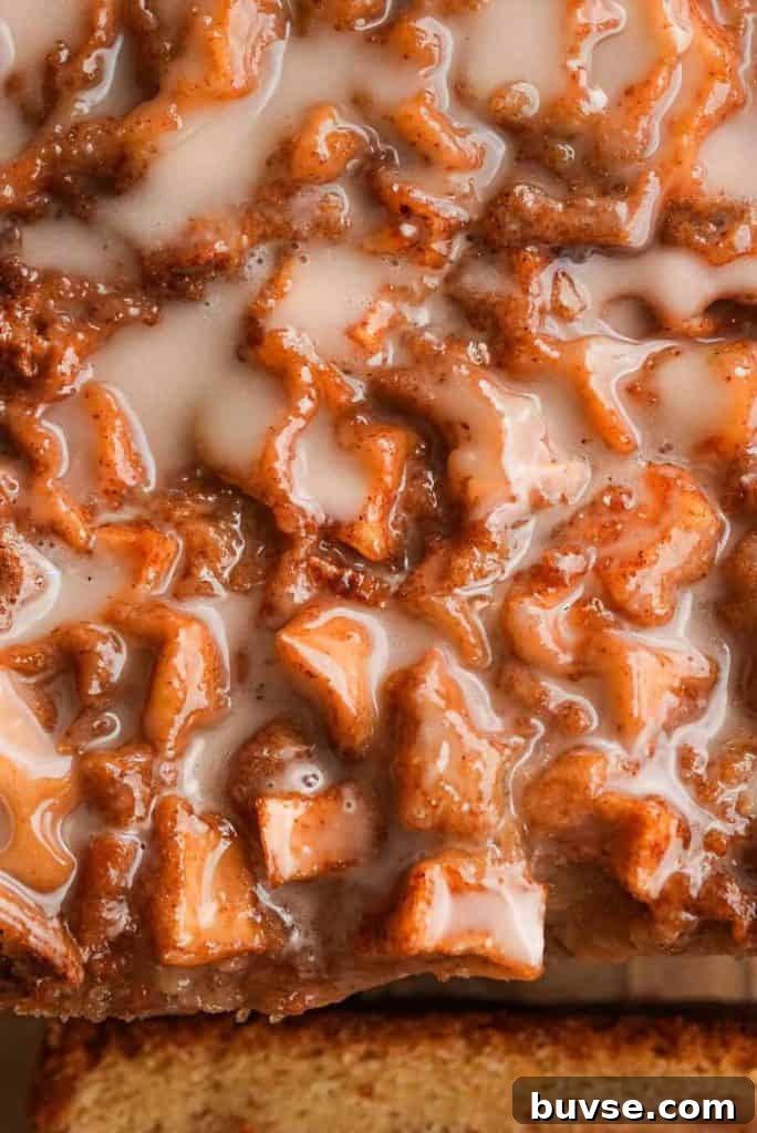 Close-up of the glazed top of apple fritter bread, highlighting cinnamon-coated apple chunks and icing drizzle.