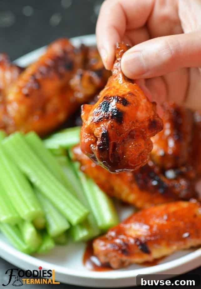 holding one bbq sauce chicken drumette with fingers