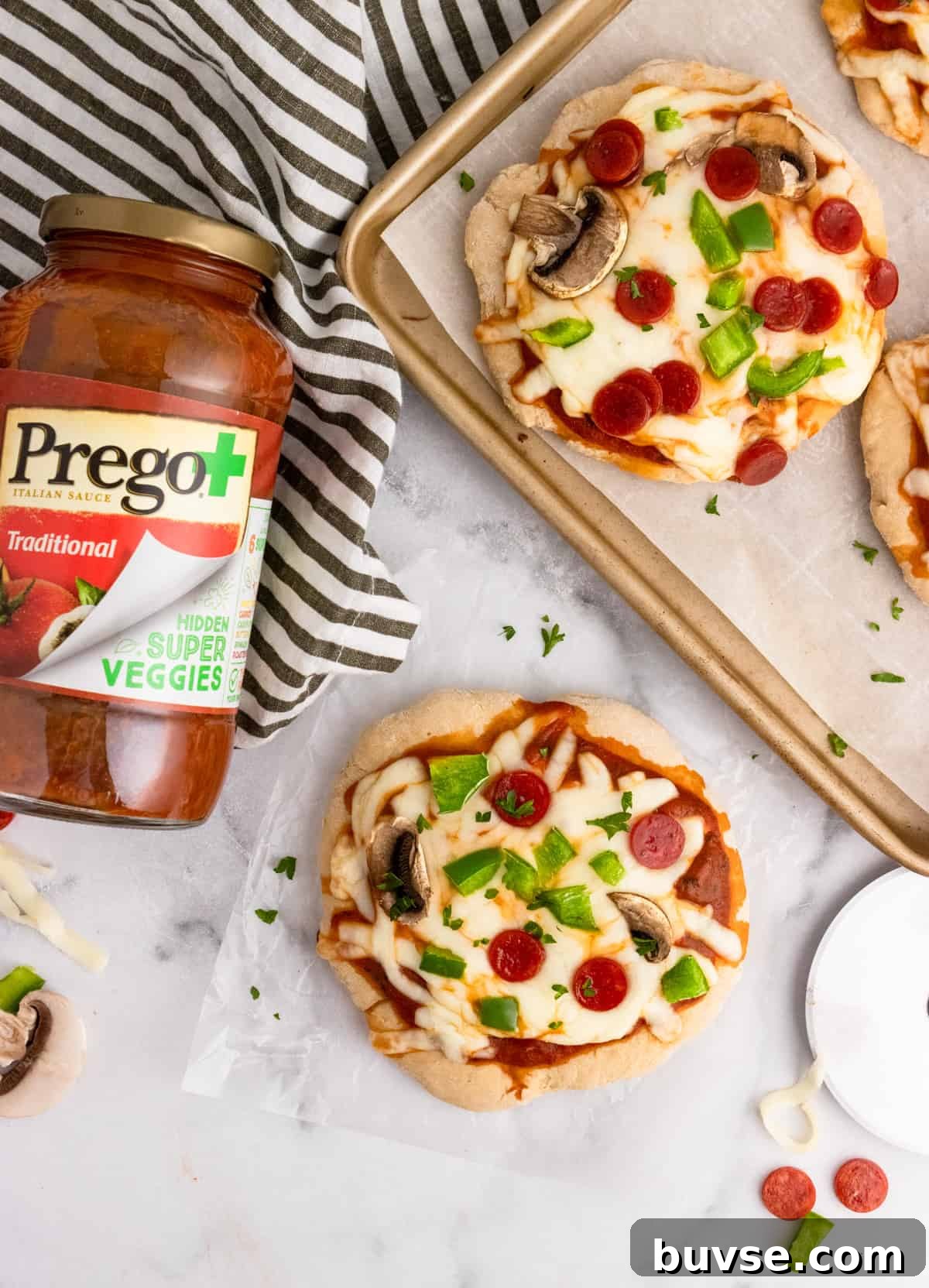 Overhead shot of pizzas on pan with tomato sauce jar.