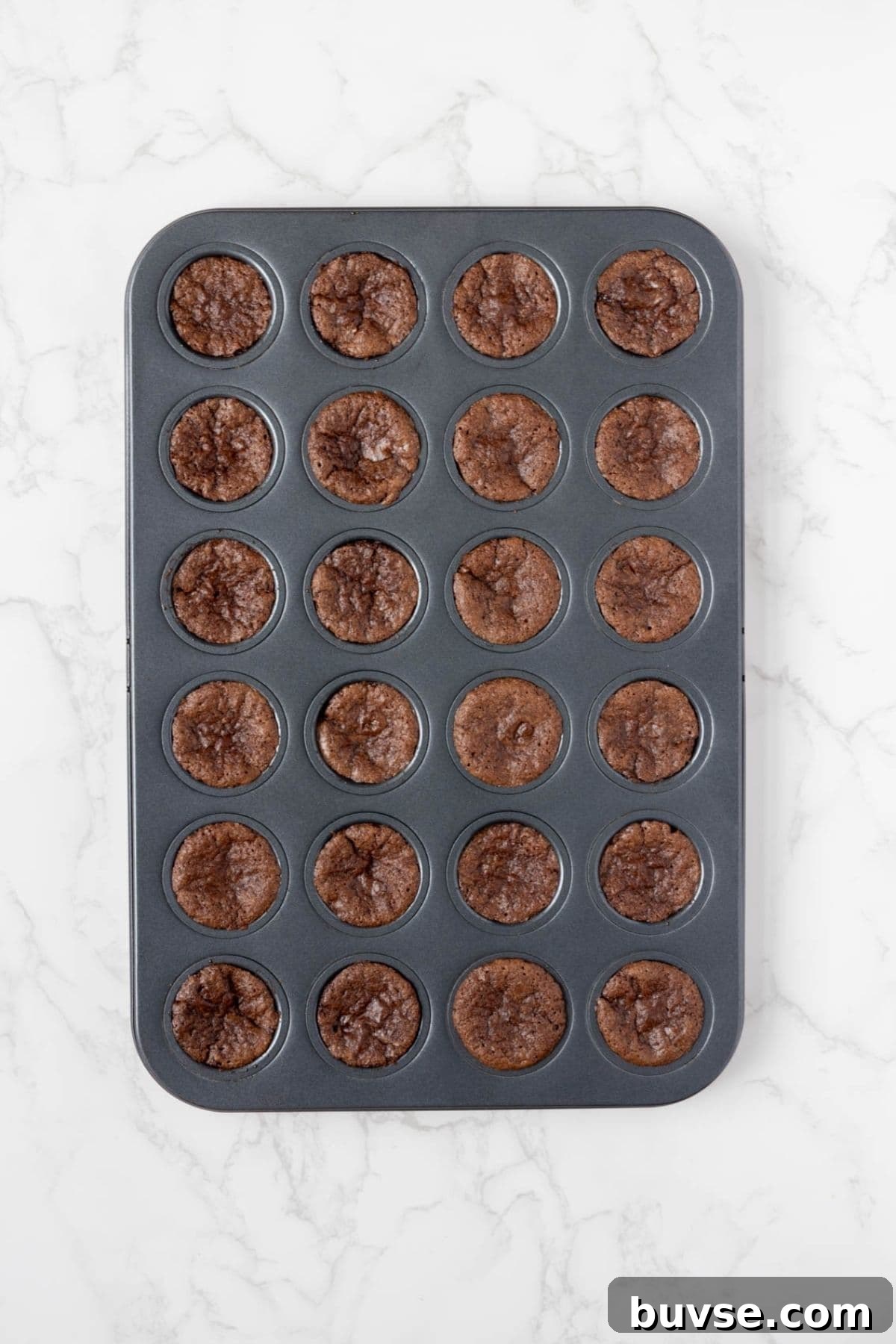 Fudgy Chocolate Sourdough Brownie Bites 6 Freshly baked sourdough chocolate brownie bites cooling in a mini muffin pan.
