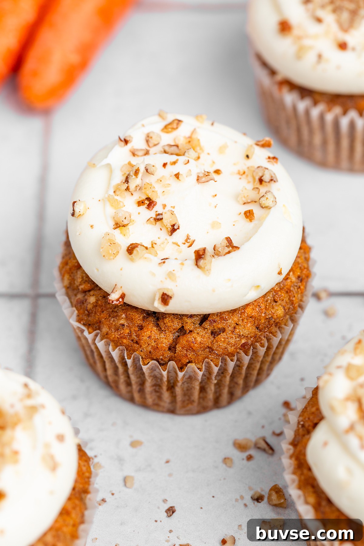 Frosted carrot cake cupcakes with chopped nuts on top