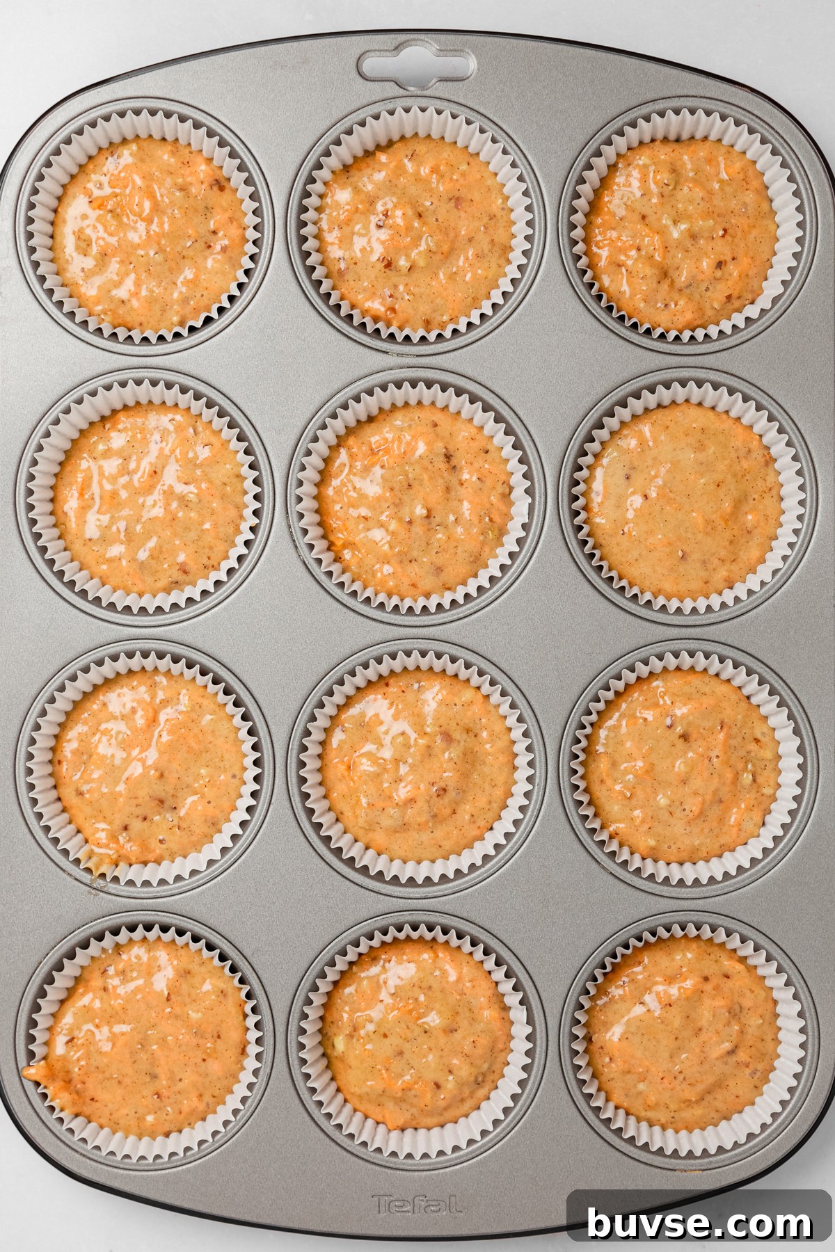 Cupcake pan filled with carrot cake cupcakes batter before baking