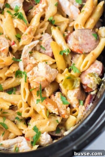 Creamy slow cooker Cajun chicken pasta with sausage, peppers and parmesan cheese.