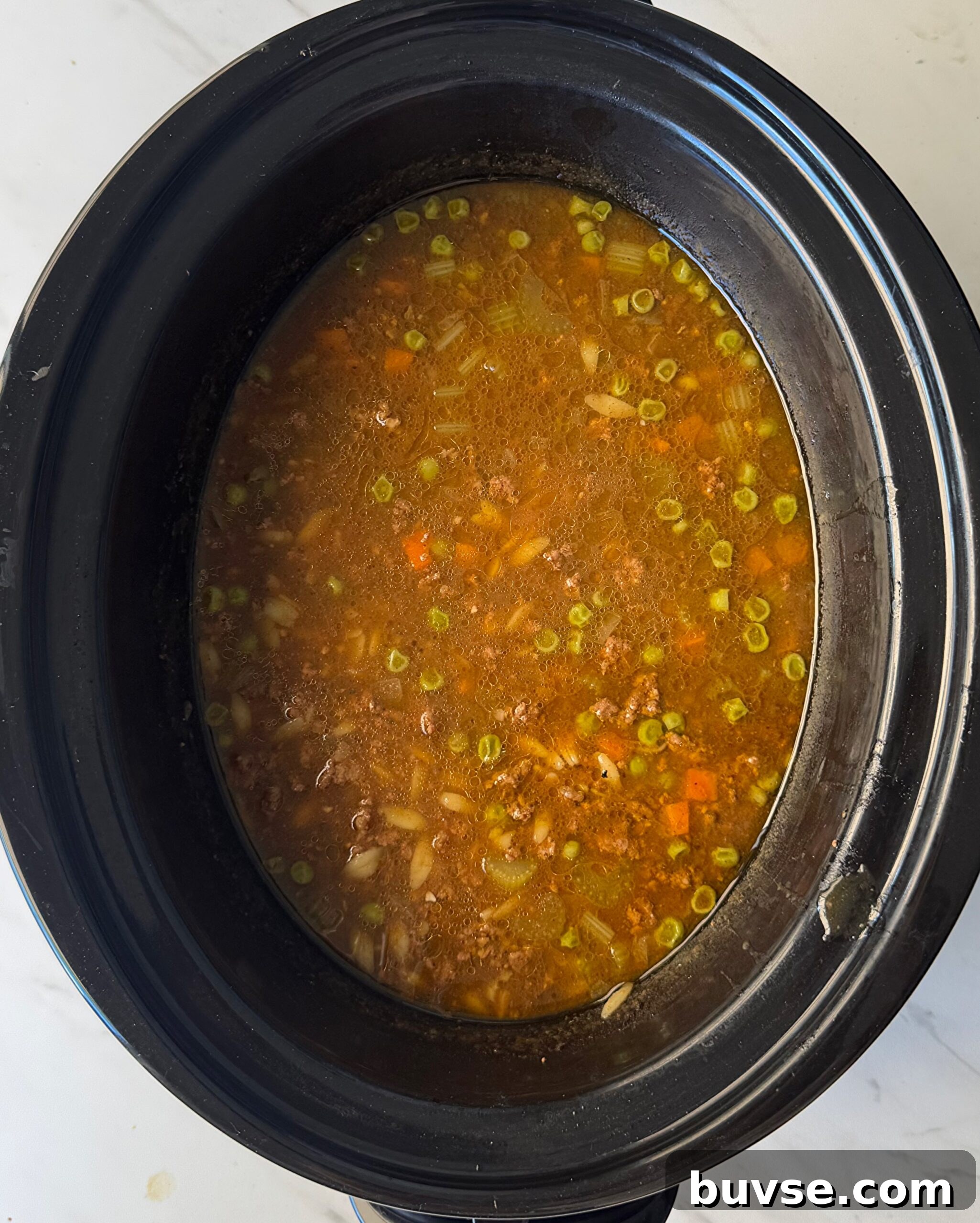 Slow Cooker Beef and Pumpkin Orzo Soup 5 overhead shot of cooked Beef Pumpkin Orzo Soup in a black slow cooker