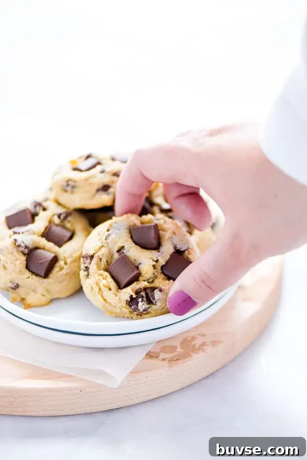 Gluten-Free Sourdough Chocolate Chip Cookies Recipe 3 a hand reaching to pick up a gluten free sourdough chocolate chip cookie