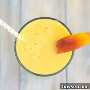 Overhead image of a glass filled with Peach Smoothie garnished with a sliced peach.