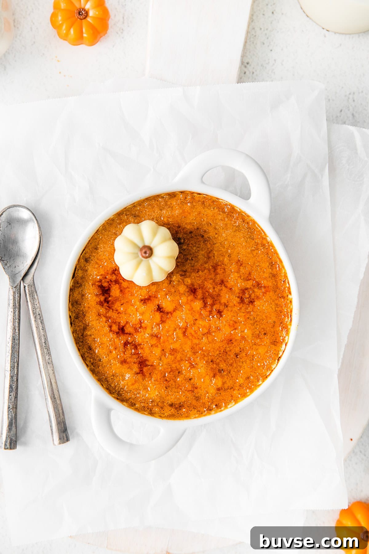 Silky Pumpkin Crème Brûlée Recipe 2 Pumpkin Creme Brulee sitting on parchment paper.