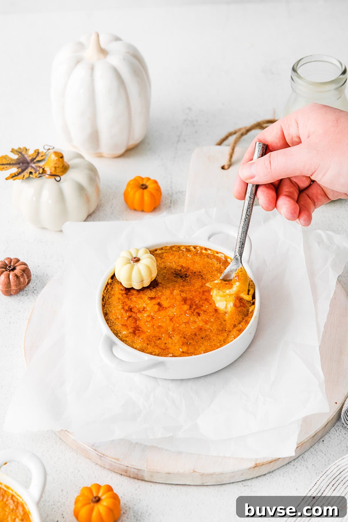 Silky Pumpkin Crème Brûlée Recipe 9 A hand holding a spoon taking a bite of Pumpkin Creme Brulee.