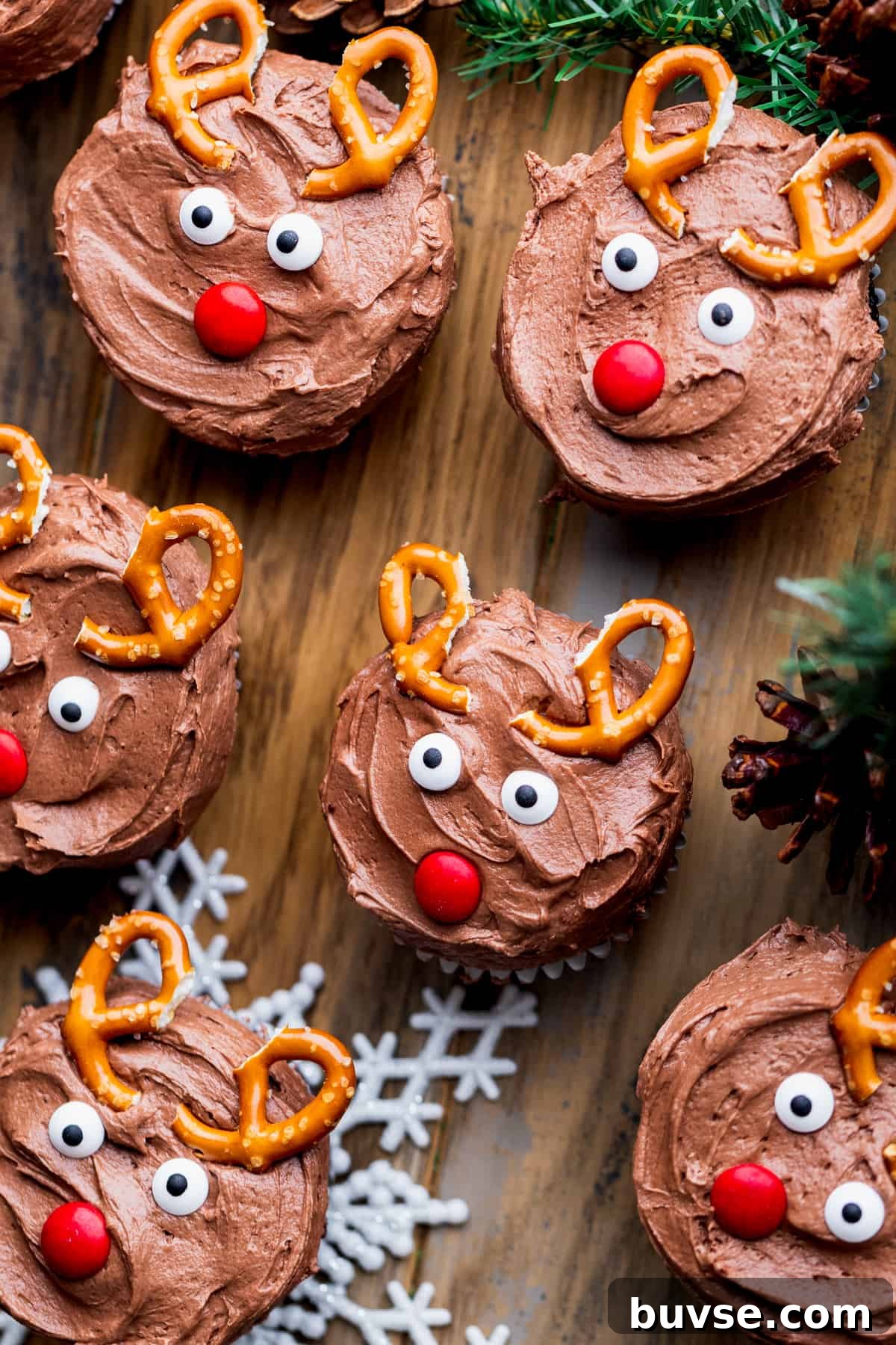 Array of reindeer cupcakes on a wood board.