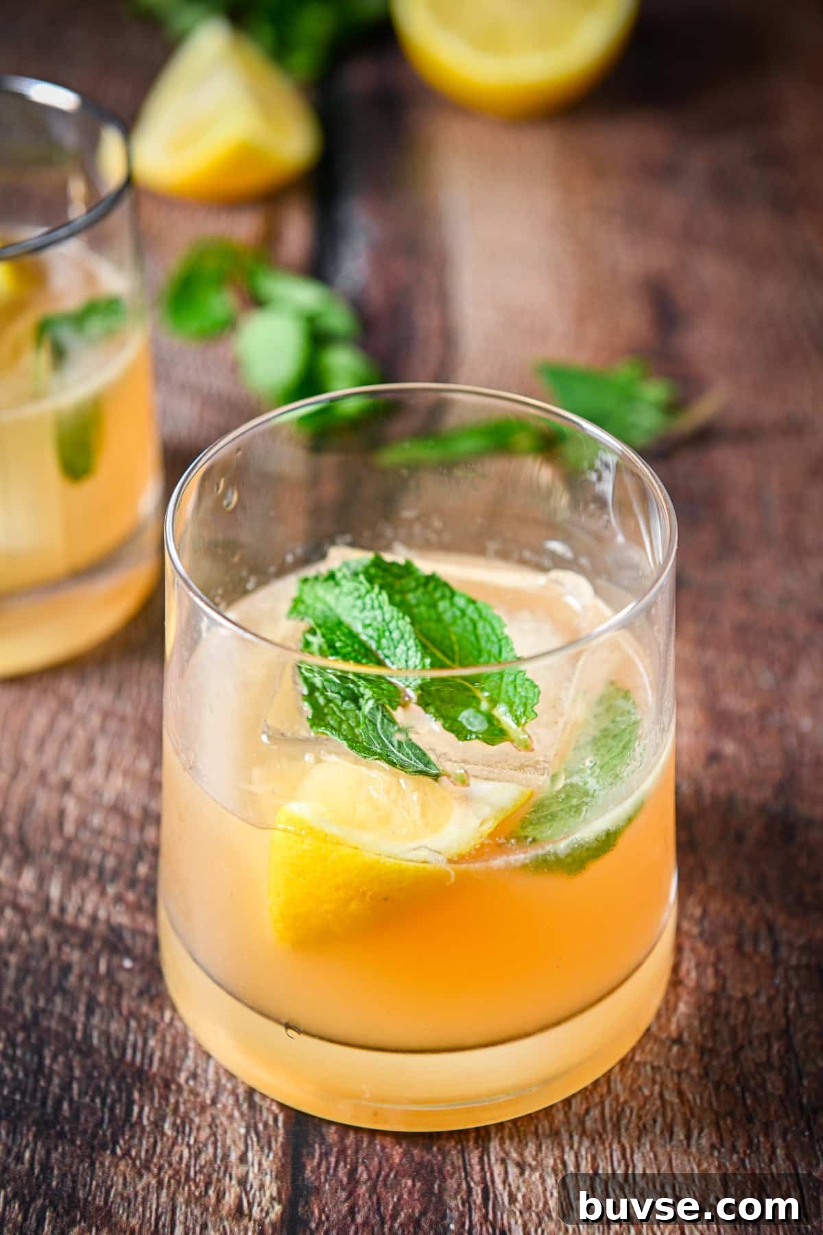 Close up of a glass with the smash cocktail in it with mint and lemon