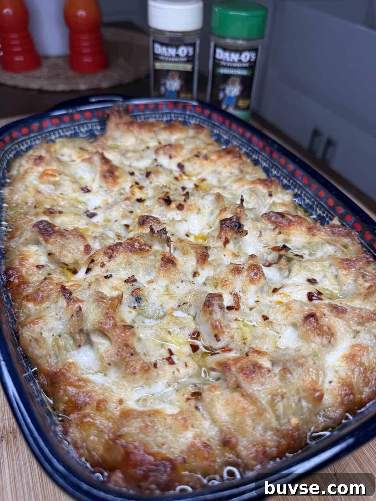 Baked artichoke dip in a dish with crackers