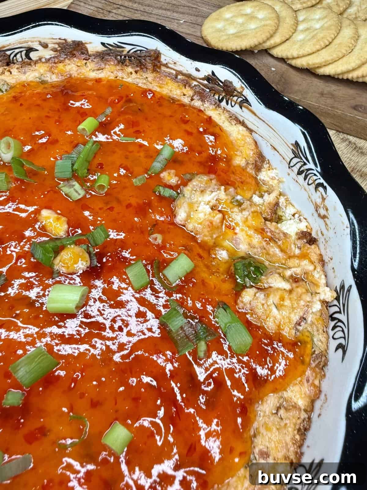 Warm Christmas-themed dip topped with pepper jelly and green onions
