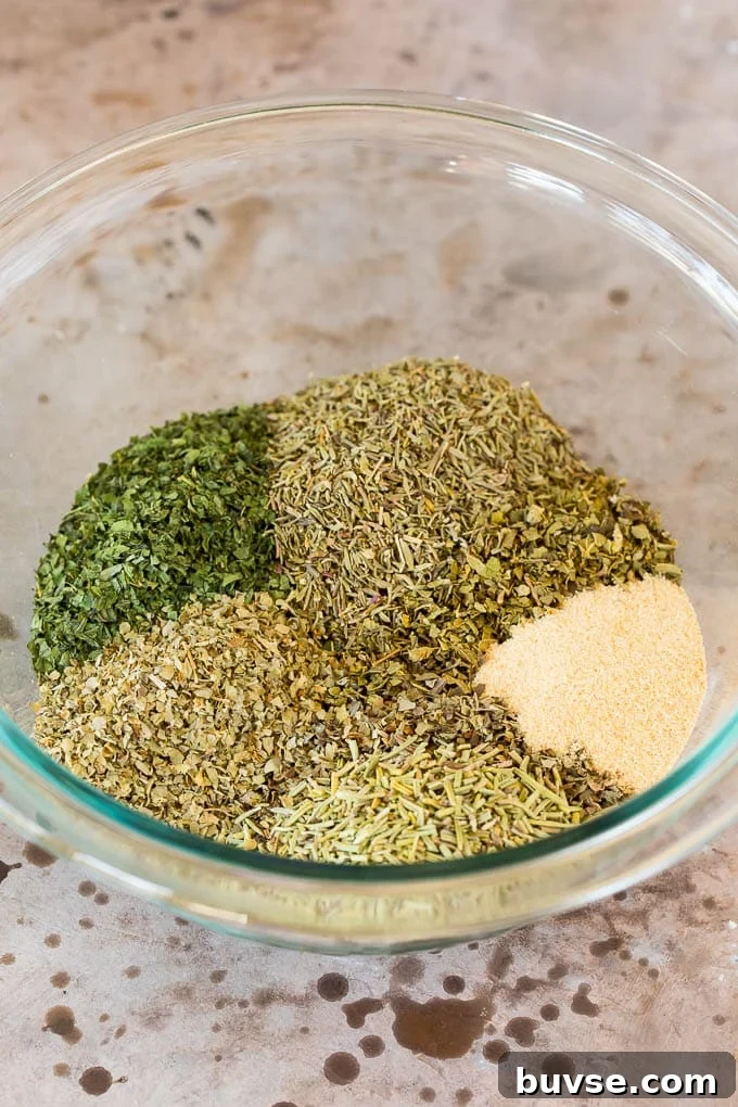 A mixing bowl with dried herbs and garlic powder in it.