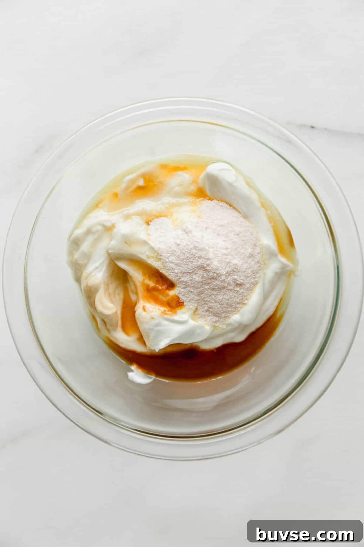 Greek yogurt, vanilla pudding mix and maple syrup in a clear mixing bowl.