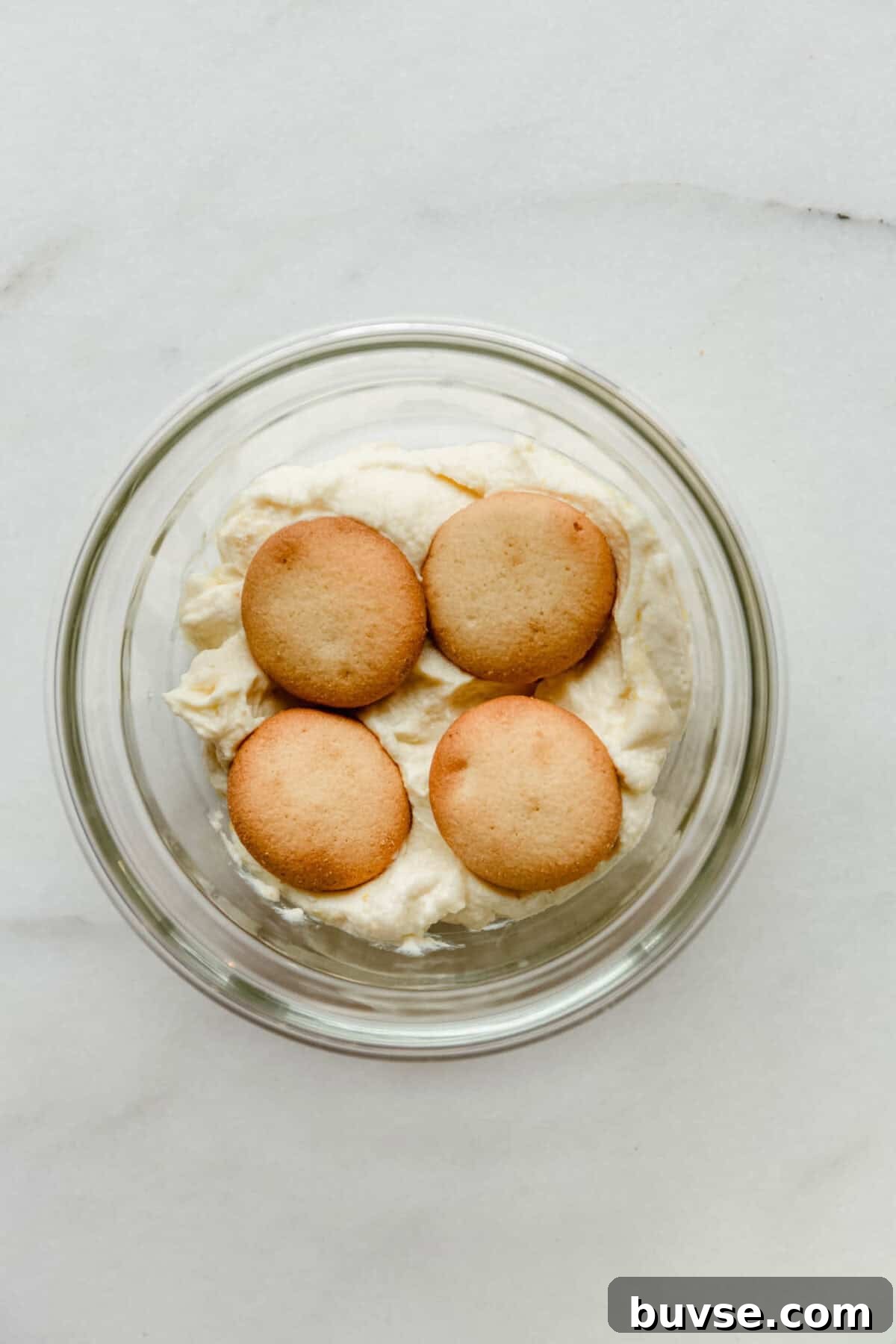 nilla wafers on greek yogurt pudding in a clear container.