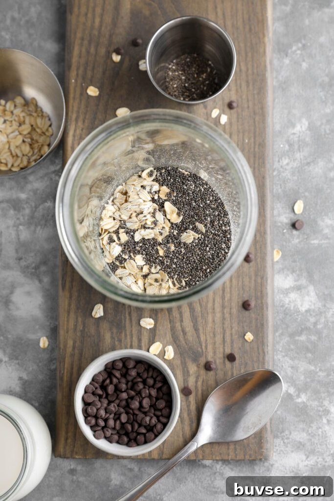 Brownie Batter Overnight Oats Recipe for Chocolate Lovers 5 oats and chia seeds in mason jar on wooden board with dark chocolate chips and oats scattered with a spoon