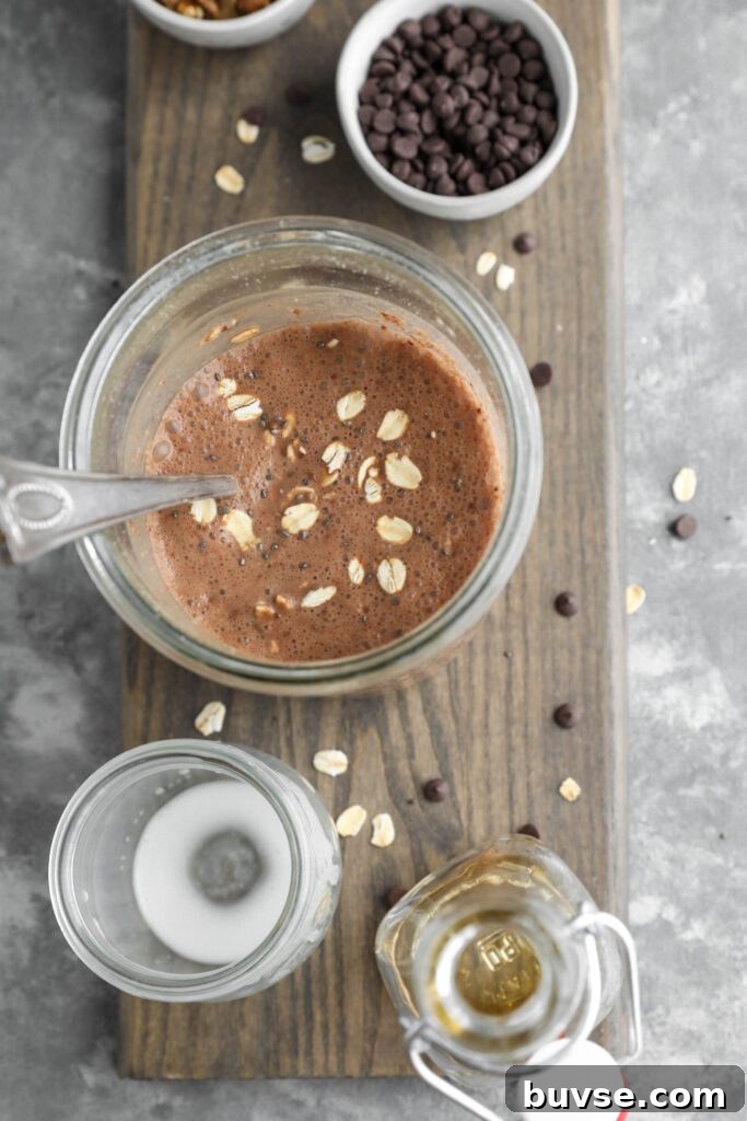 Brownie Batter Overnight Oats Recipe for Chocolate Lovers 7 brownie batter overnight oats in mason jar on wooden board with oats and dark chocolate chips scattered