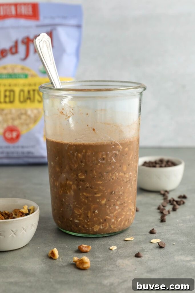 Brownie Batter Overnight Oats Recipe for Chocolate Lovers 9 brownie batter overnight oats mixed in mason jar with spoon and walnuts and dark chocolate chips scattered