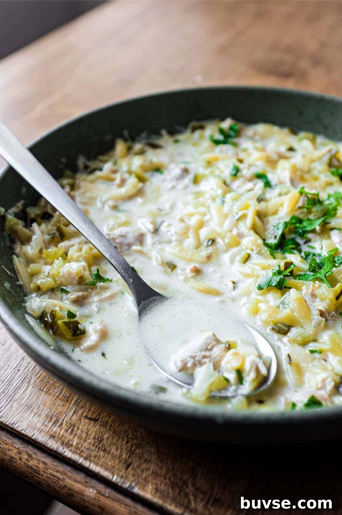 Greek Lemon Orzo Soup with Chicken | cookeatworld.com A bowl of Greek lemon orzo soup with chicken with a spoon