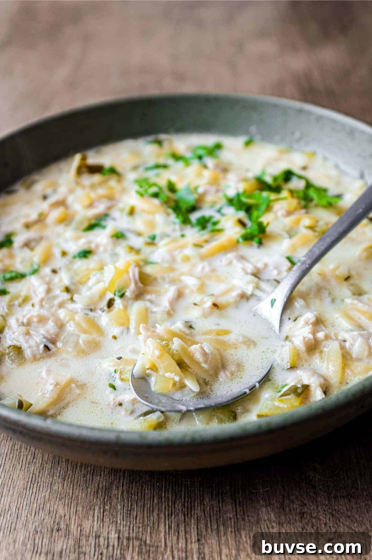 Greek Lemon Orzo Soup with Chicken | cookeatworld.com A bowl of Greek lemon orzo soup with chicken with a spoon