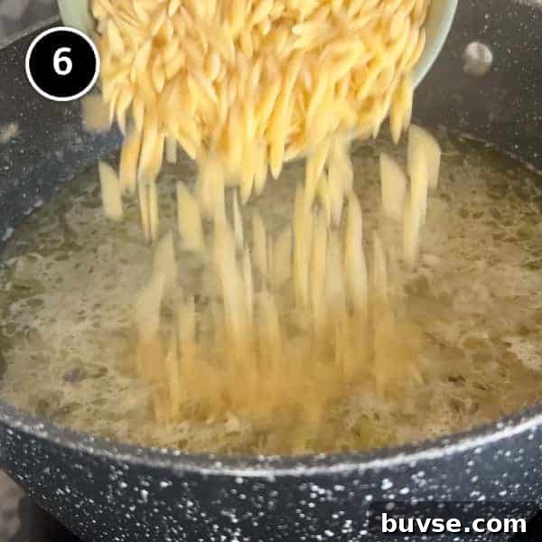 Greek Lemon Orzo Soup with Chicken | cookeatworld.com A small bowl of orzo pasta is poured into a pan of bubbling soup.