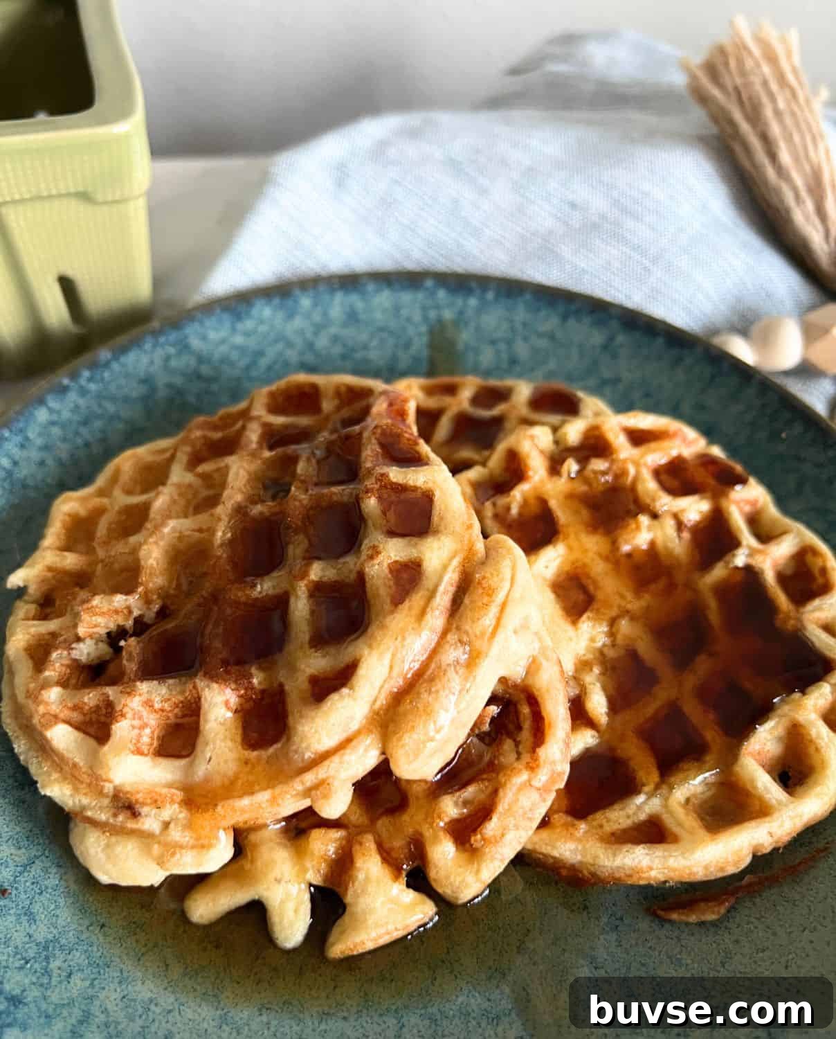 High-Protein Weight Watchers Waffles 2 Protein waffles on a blue plate topped with maple syrup.