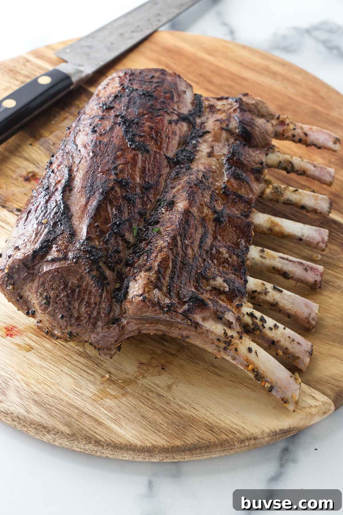 A Frenched rack of lamb on a cutting board.