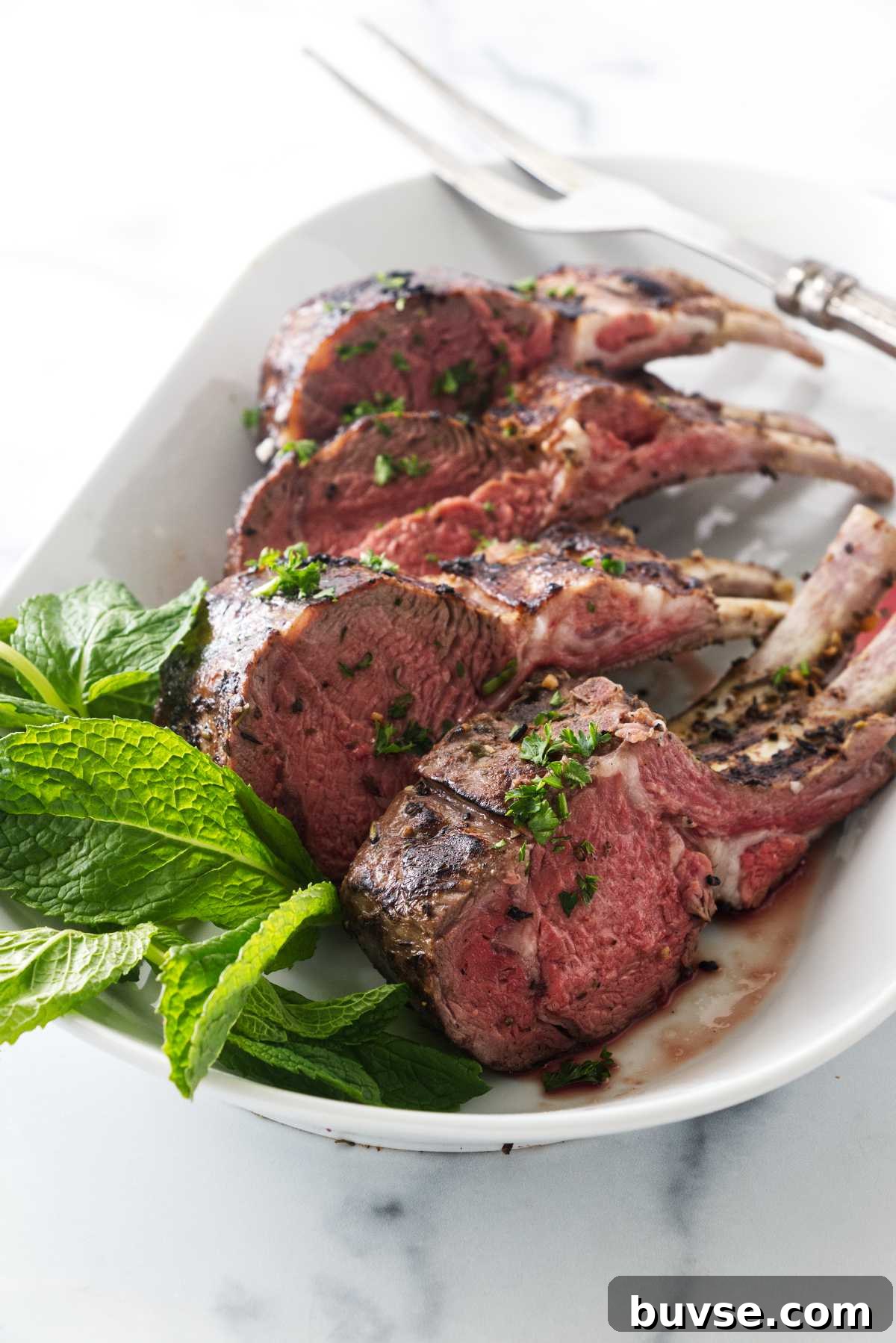 Lamb in a serving plate next to a large fork.