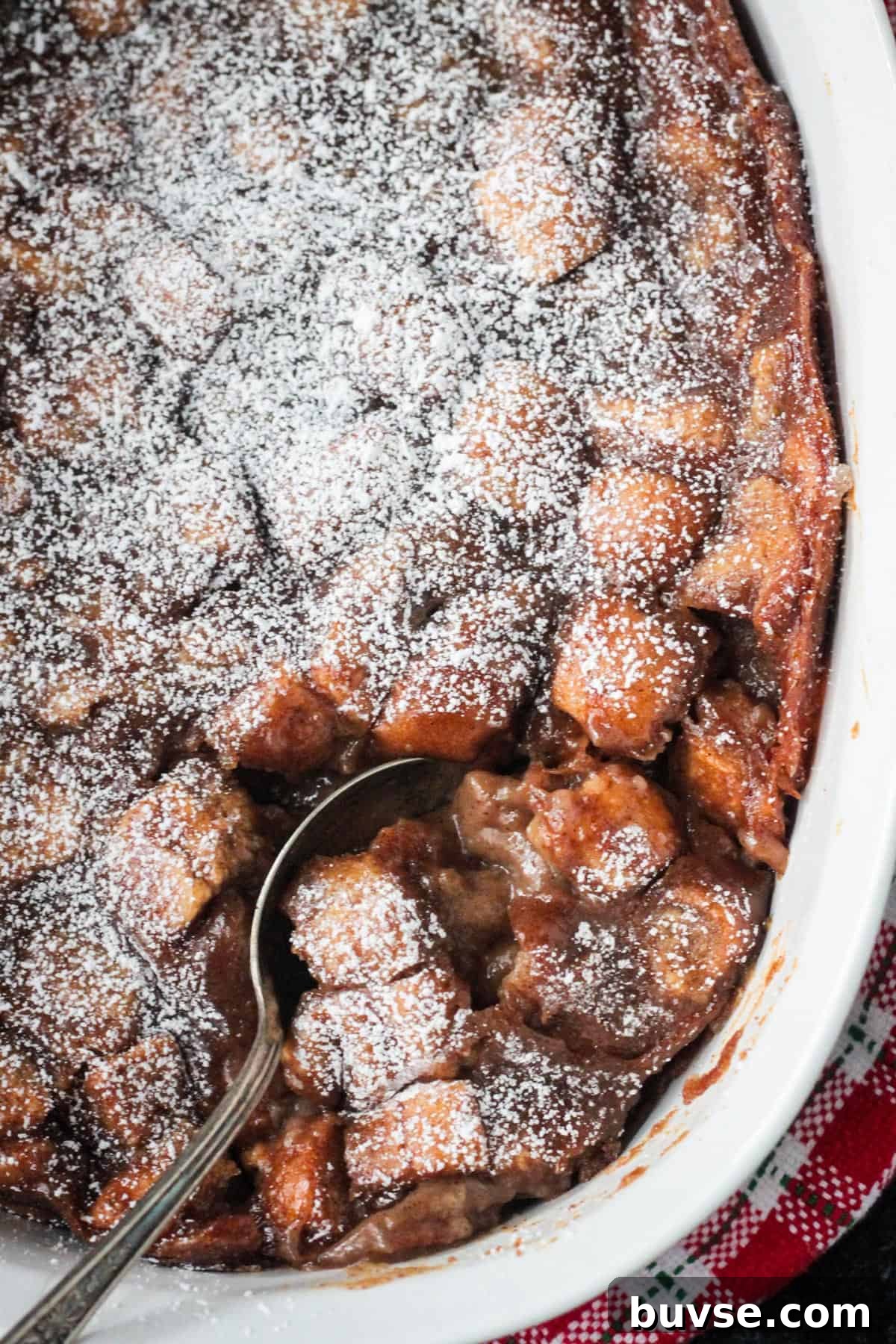 Creamy Vegan Bread Pudding Recipe with Cinnamon 14 Close up of a serving spoon in a dish of bread pudding.