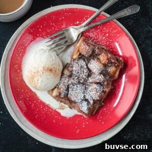 Slice of vegan bread pudding on a red plate with a scoop of vanilla ice cream.