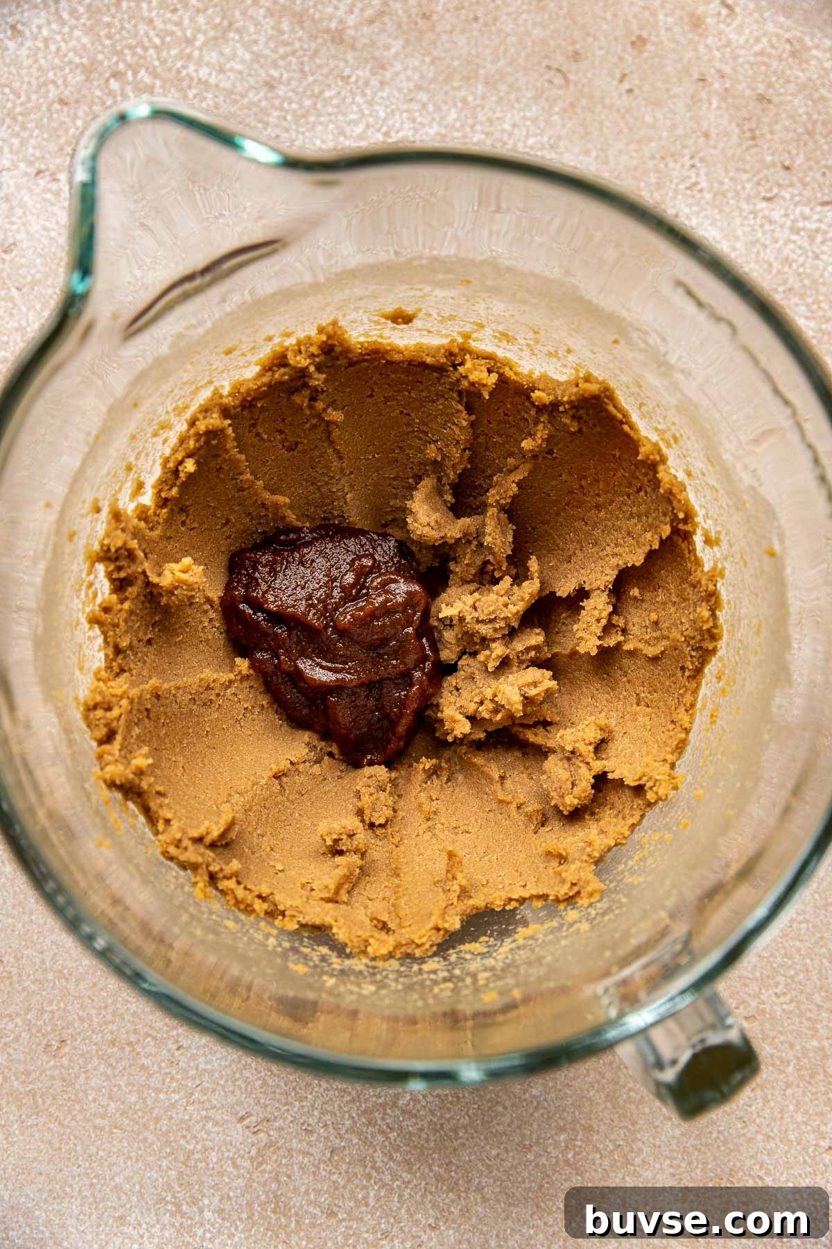 cookie dough in a glass mixing bowl with apple butter.