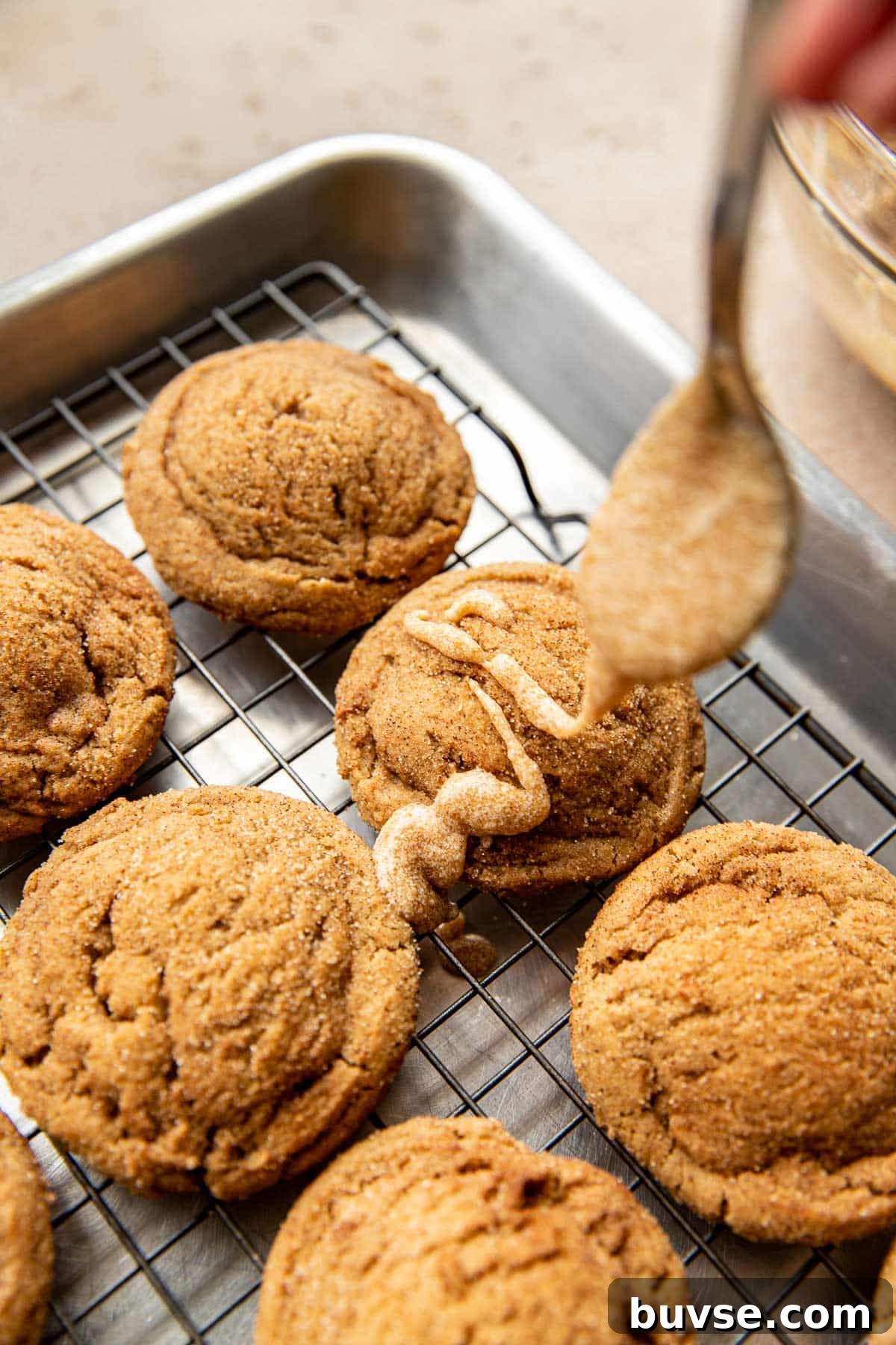 glaze being drizzled over cookies with a spoon.
