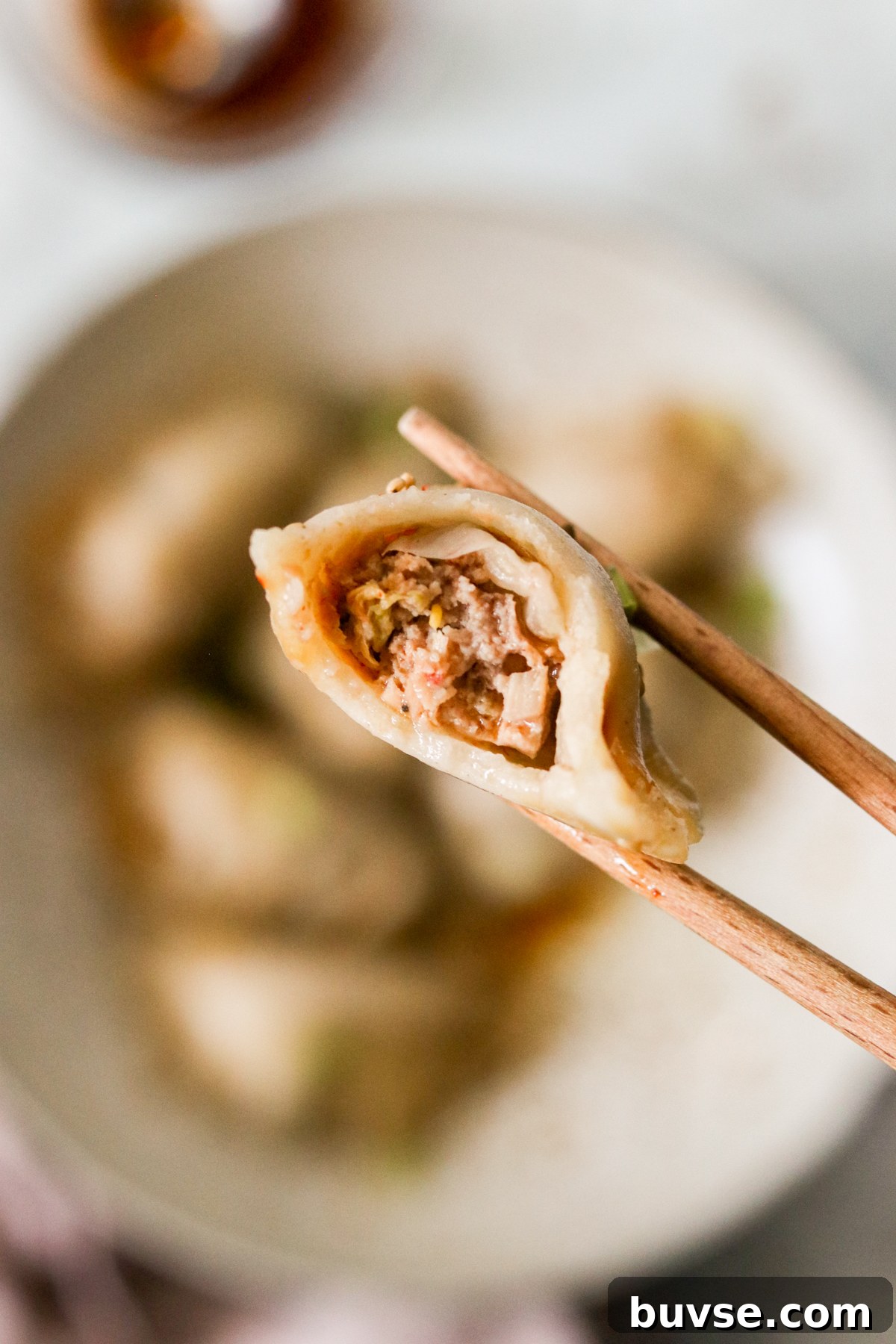 Korean dumpling on a chopstick with a bite taken out
