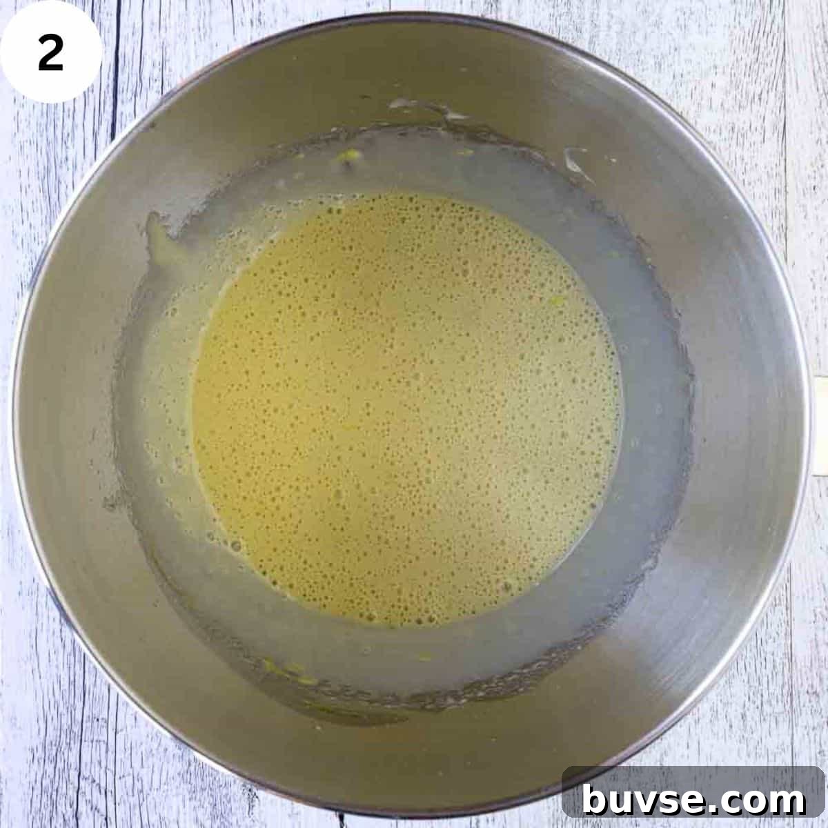Yellow frothy batter in stainless steel bowl.