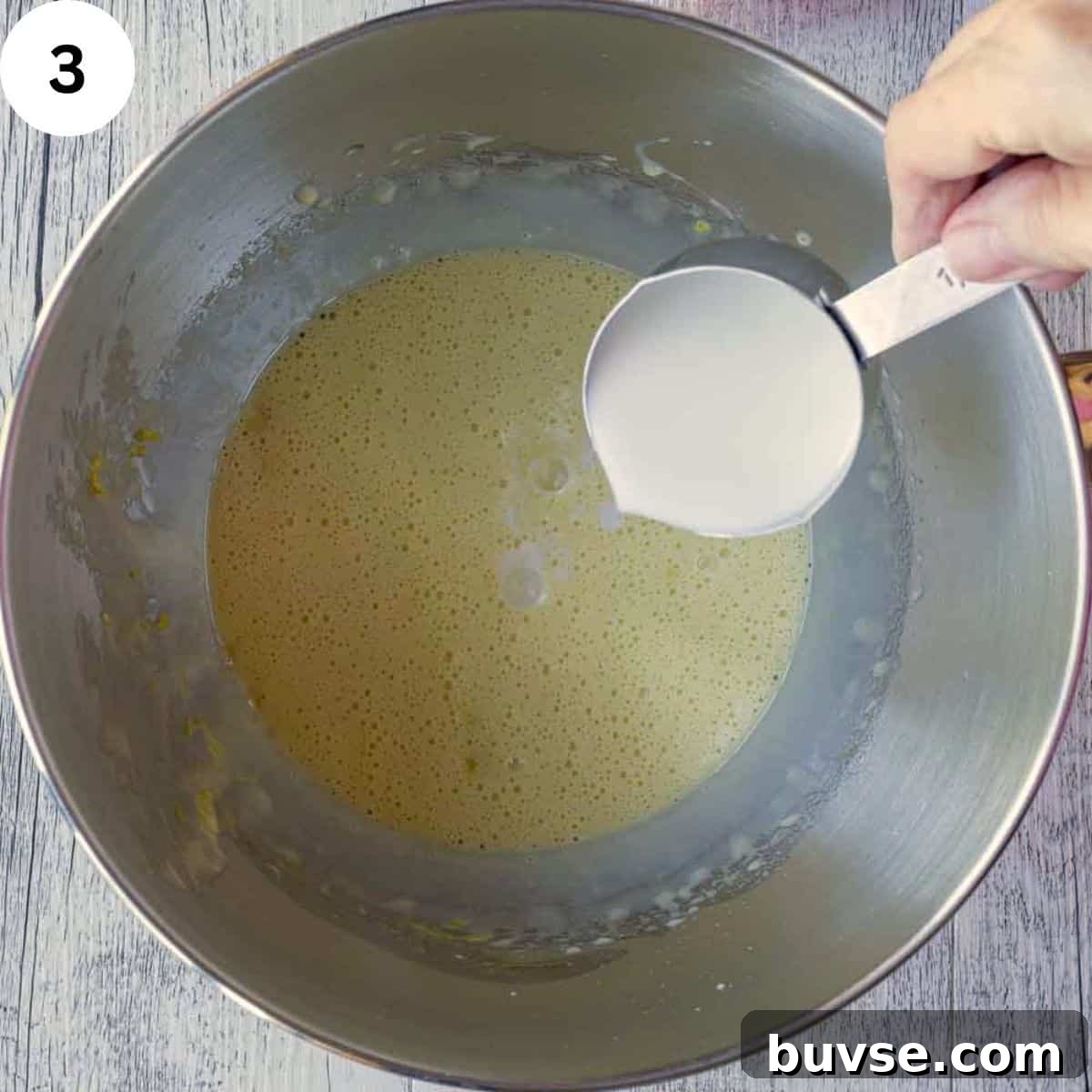 Adding milk to yellow frothy batter.