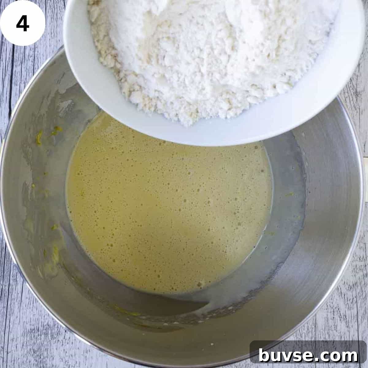 Adding flour to yellow frothy batter.
