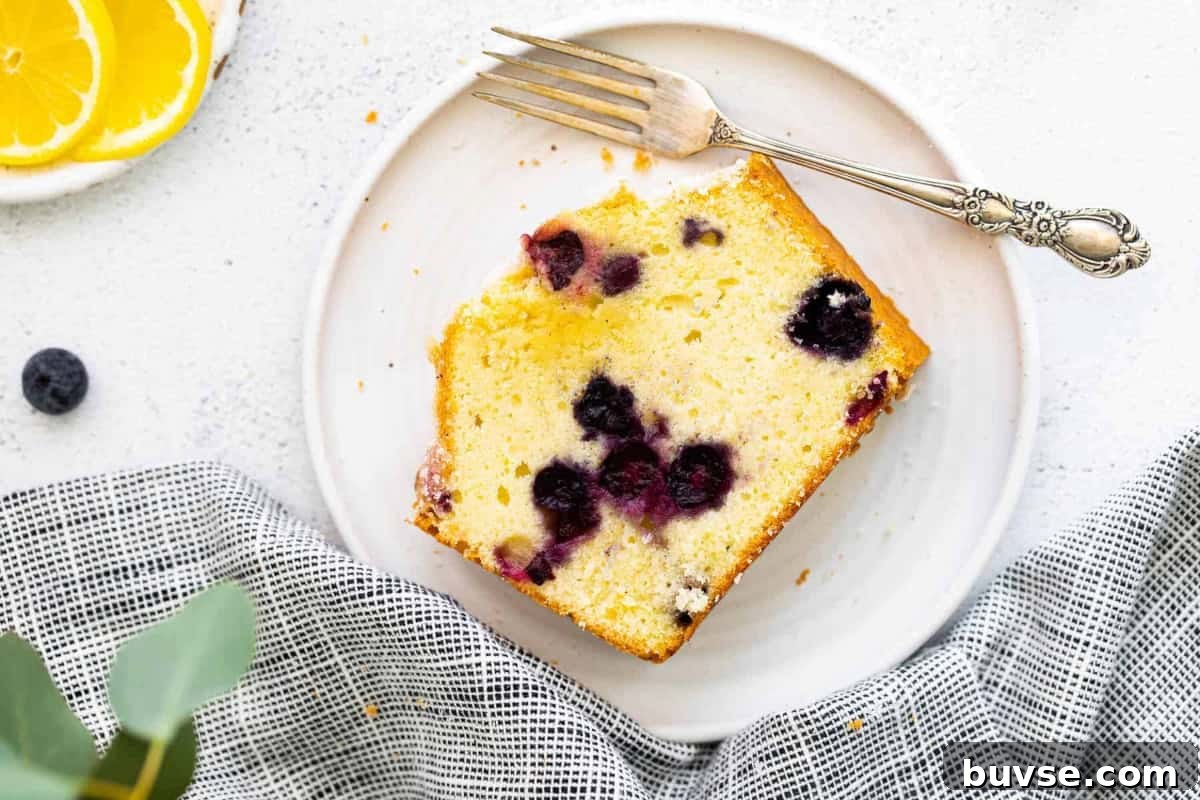 a slice of blueberry lemon pound cake on a plate with a fork.