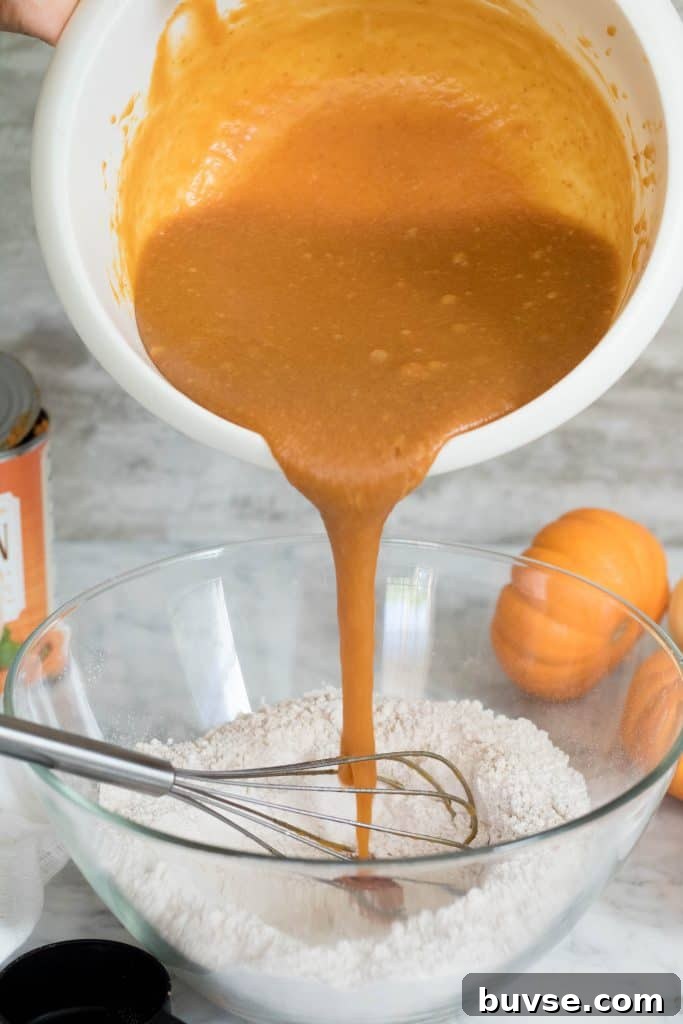 The wet ingredients of the pumpkin muffins getting poured onto the dry ingredients.