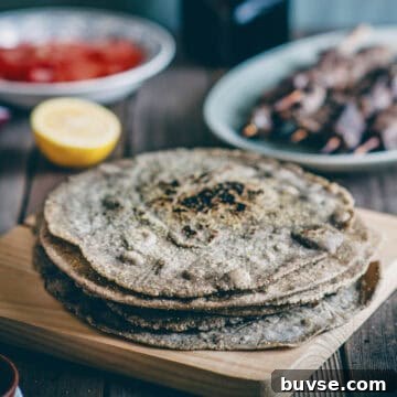 Gluten-Free Buckwheat Pita Bread Recipe 15 a stack of buckwheat pita breads on a wooden board with souvlaki sticks and tomatoes in the background.
