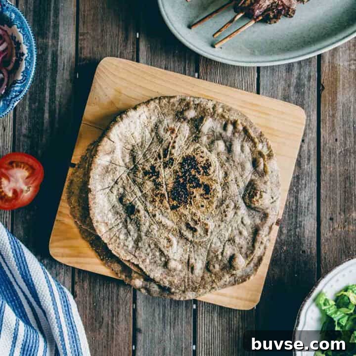 Gluten-Free Buckwheat Pita Bread Recipe 9 cooked buckwheat pita bread served on a wooden board with Greek souvlaki and condiments.