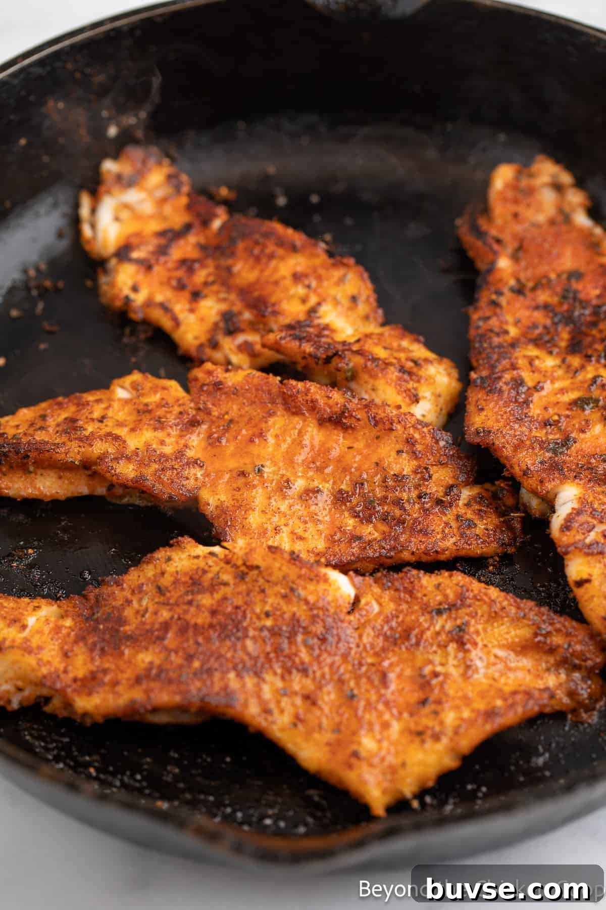 Cooked blackened fish in a cast iron skillet.