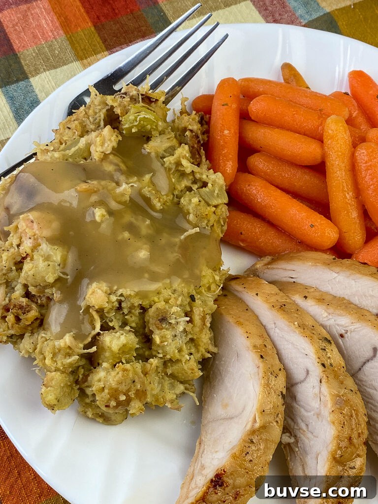 Plate with dressing coated in gravy, slices of turkey and glazed carrots
