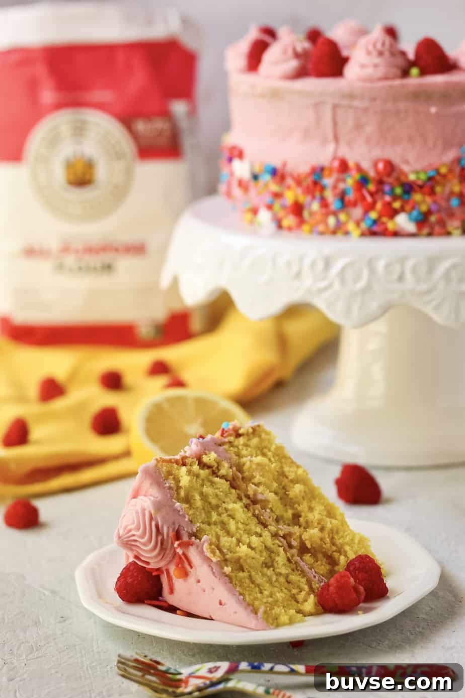 Lemon Raspberry Birthday Cake Recipe 7 side shot of lemon raspberry birthday cake on cake stand with bag of flour in the background