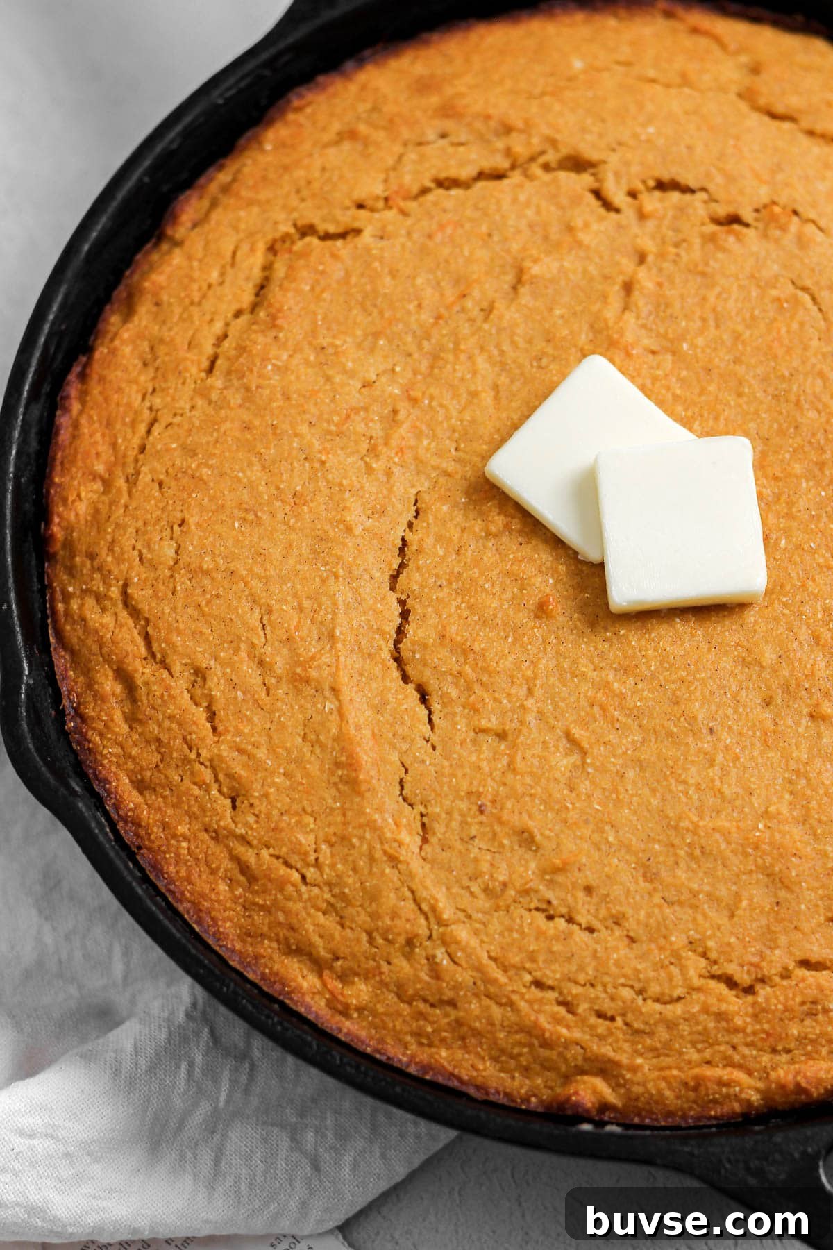 sweet potato cornbread in a cast iron skillet with butter