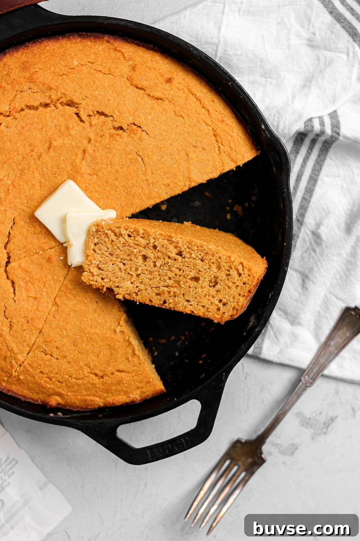 slice of sweet potato cornbread with butter in a cast iron skillet