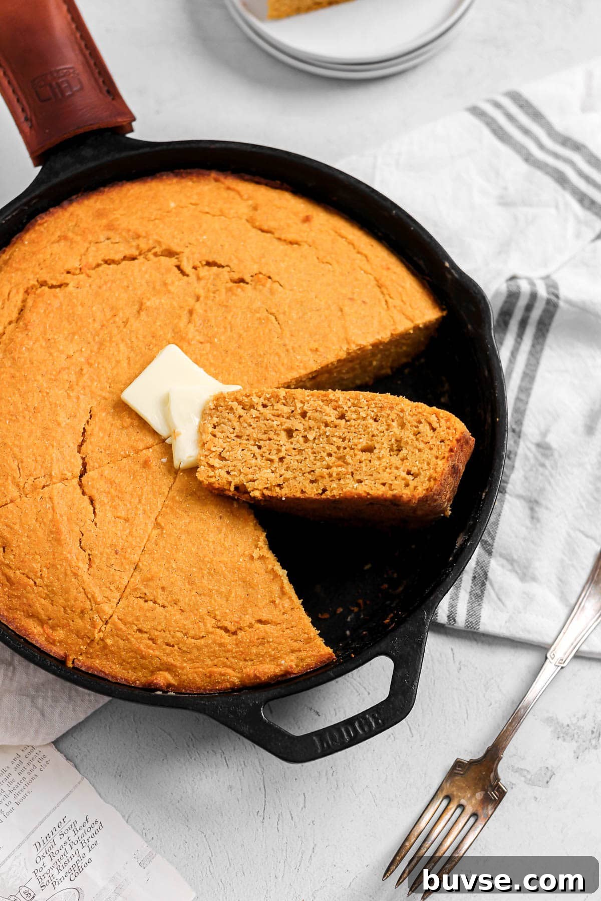 slice of sweet potato cornbread with butter in a cast iron skillet